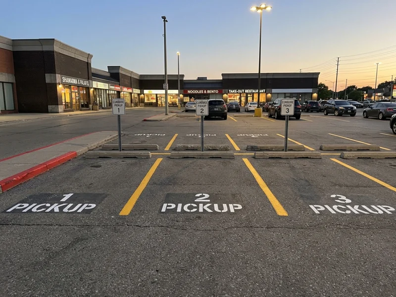 Curbside pickup stall stencils at a Toronto restaurant plaza
